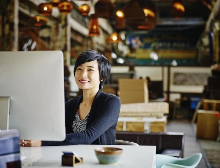 Smiling customer service representative with glasses and a headset working at a computer.