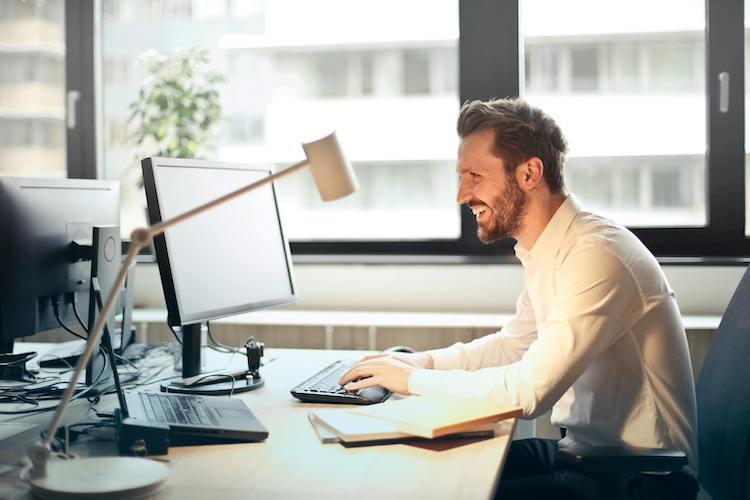 Man smiling while working at desktop computer in an office